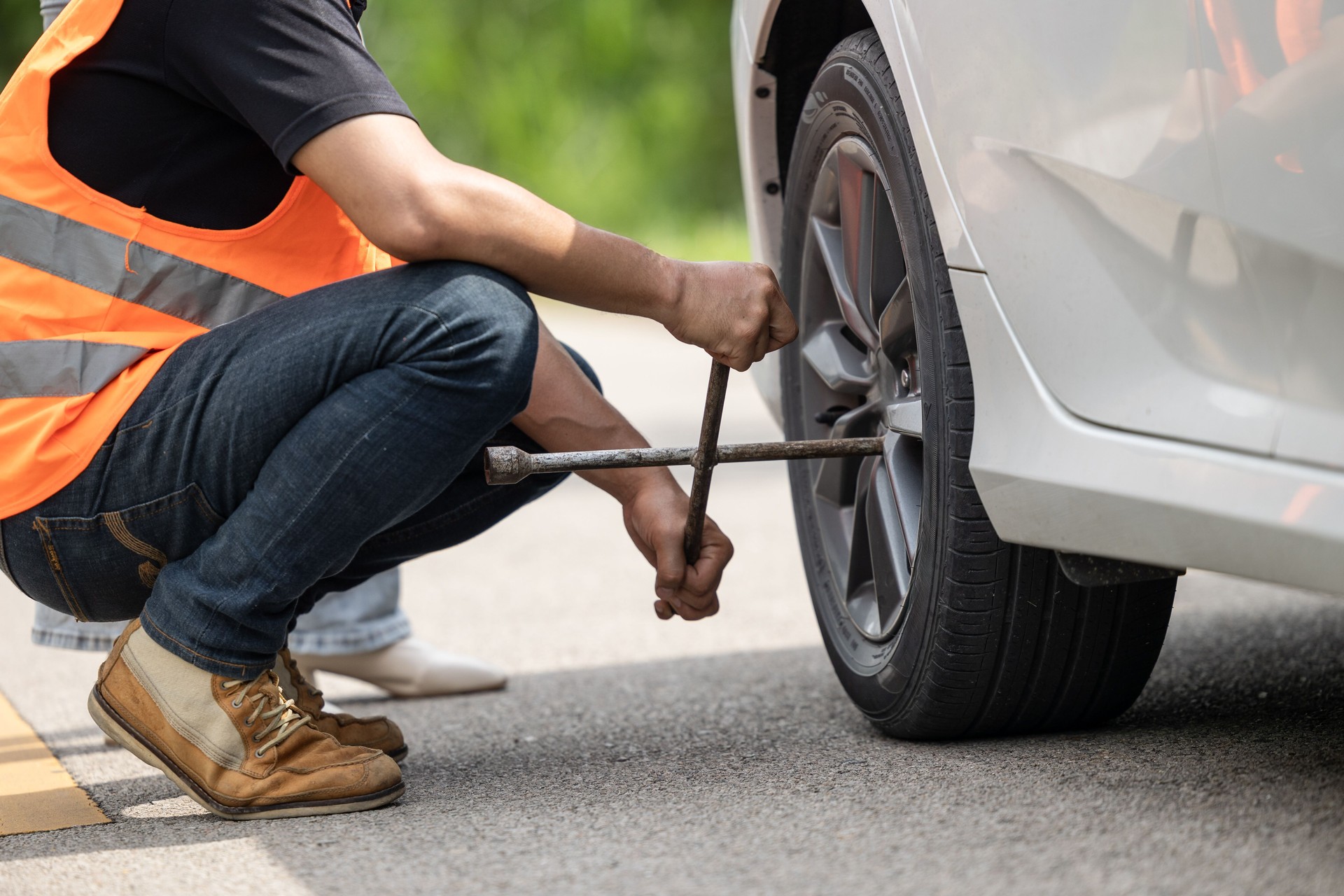 El equipo mecánico que trabaja como asistente de carretera ayuda a reemplazar el servicio de llantas desinfladas en la carretera con ropa reflectante de seguridad.